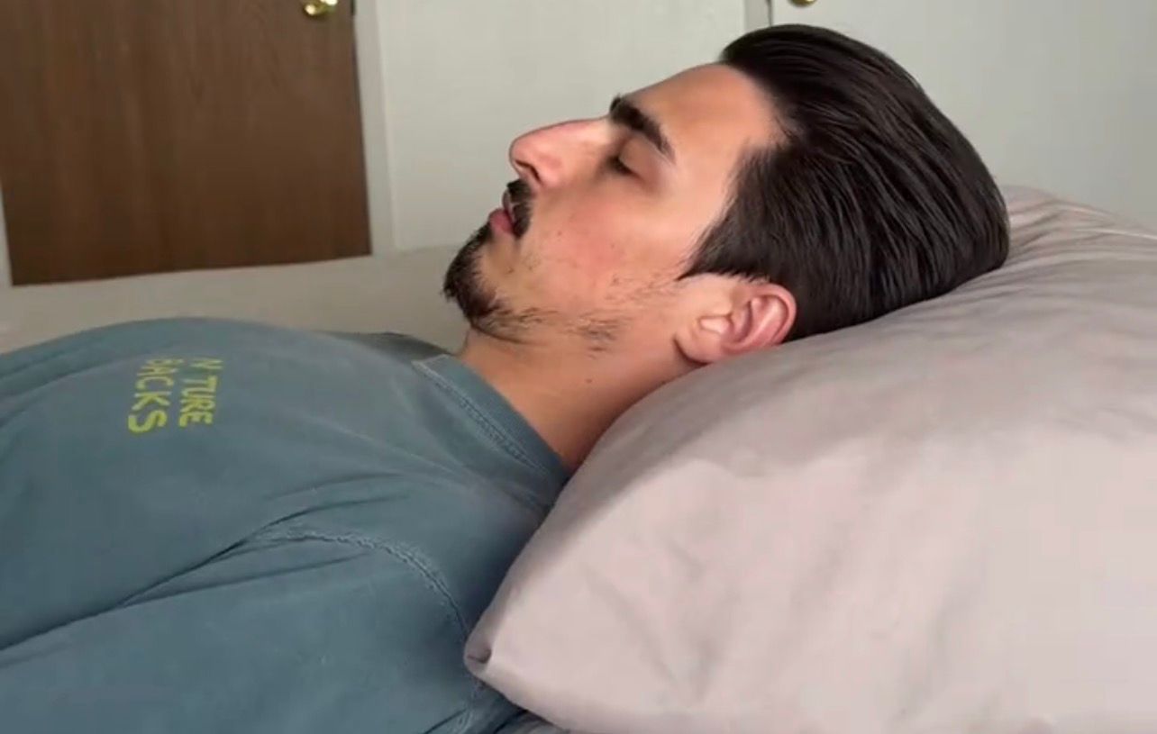 Persona durmiendo boca arriba en almohada plana, cabeza caída hacia atrás sin soporte